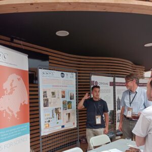 Picture of the EMFL stand at the Cryo-Ops 2024, where one of our technicians is discussing some of projects the cryogenics teams worked on.